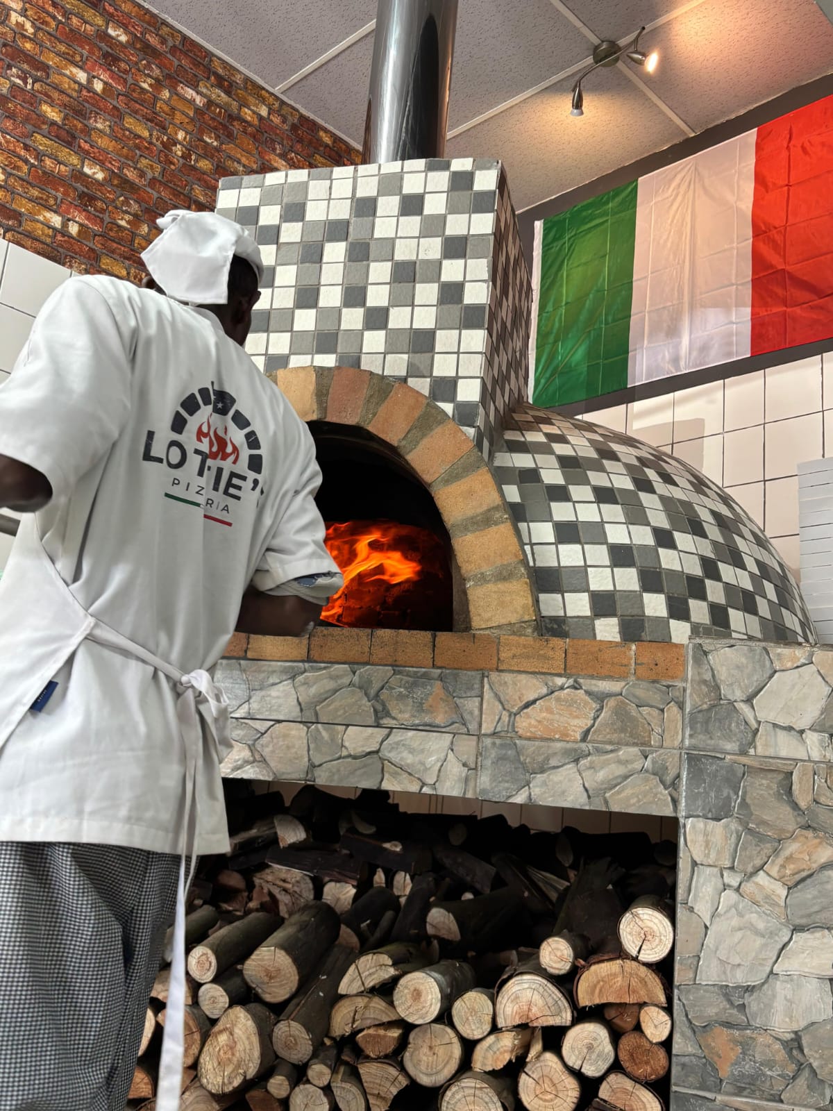 Pizza being prepared at Lottie's traditional wood-fired oven
